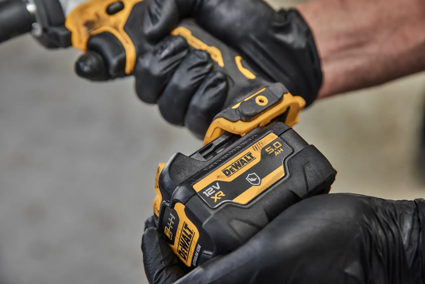 Image en gros plan d'une batterie lithium-ion DEWALT 12V MAX d'une capacité de 5 ampères-heures. La batterie est noire et jaune, avec le logo DEWALT, un indicateur d'état de la batterie et les spécifications techniques.