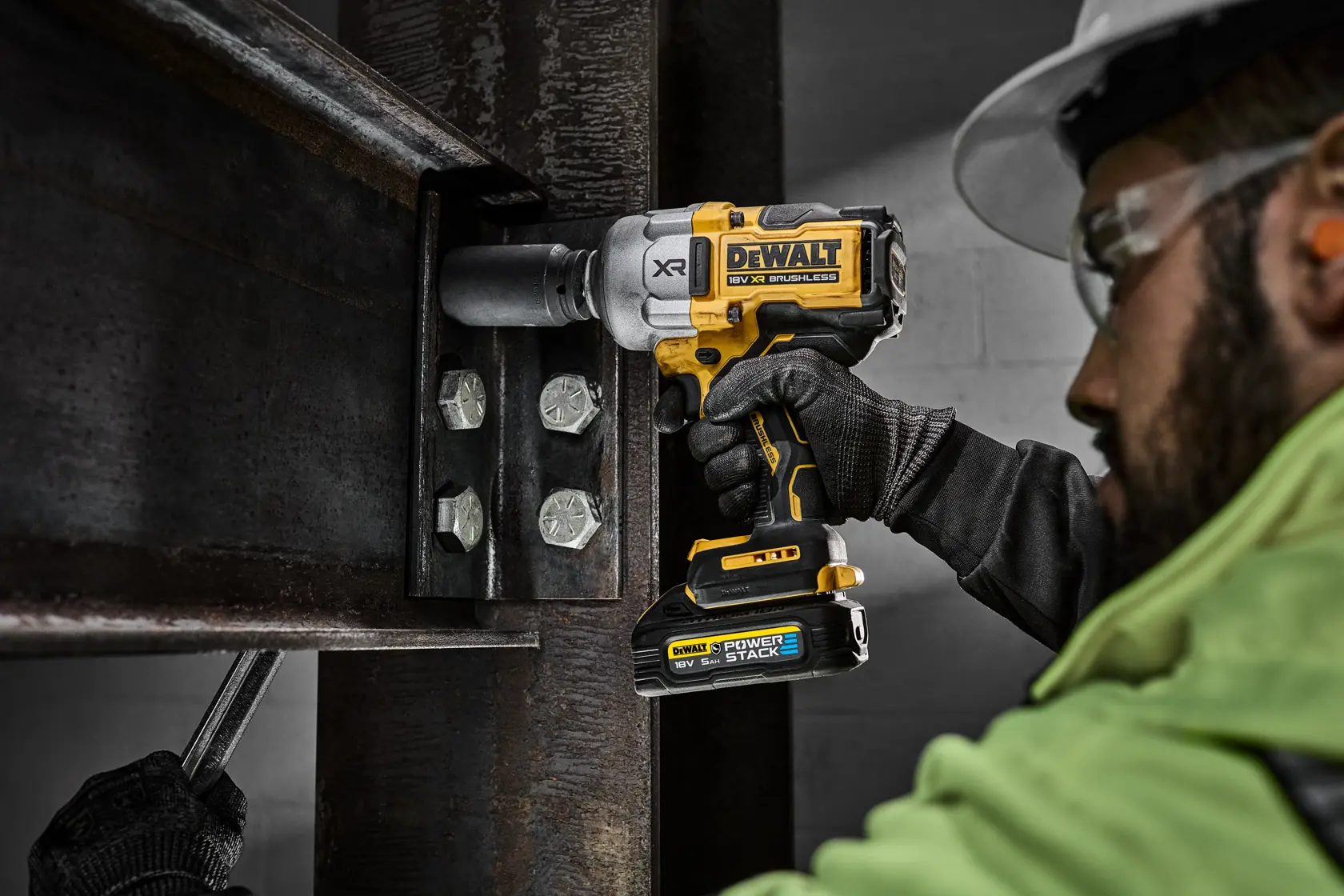 Person uses DEWALT DCF964N impact wrench to tighten bolts on a metal beam at a construction site.