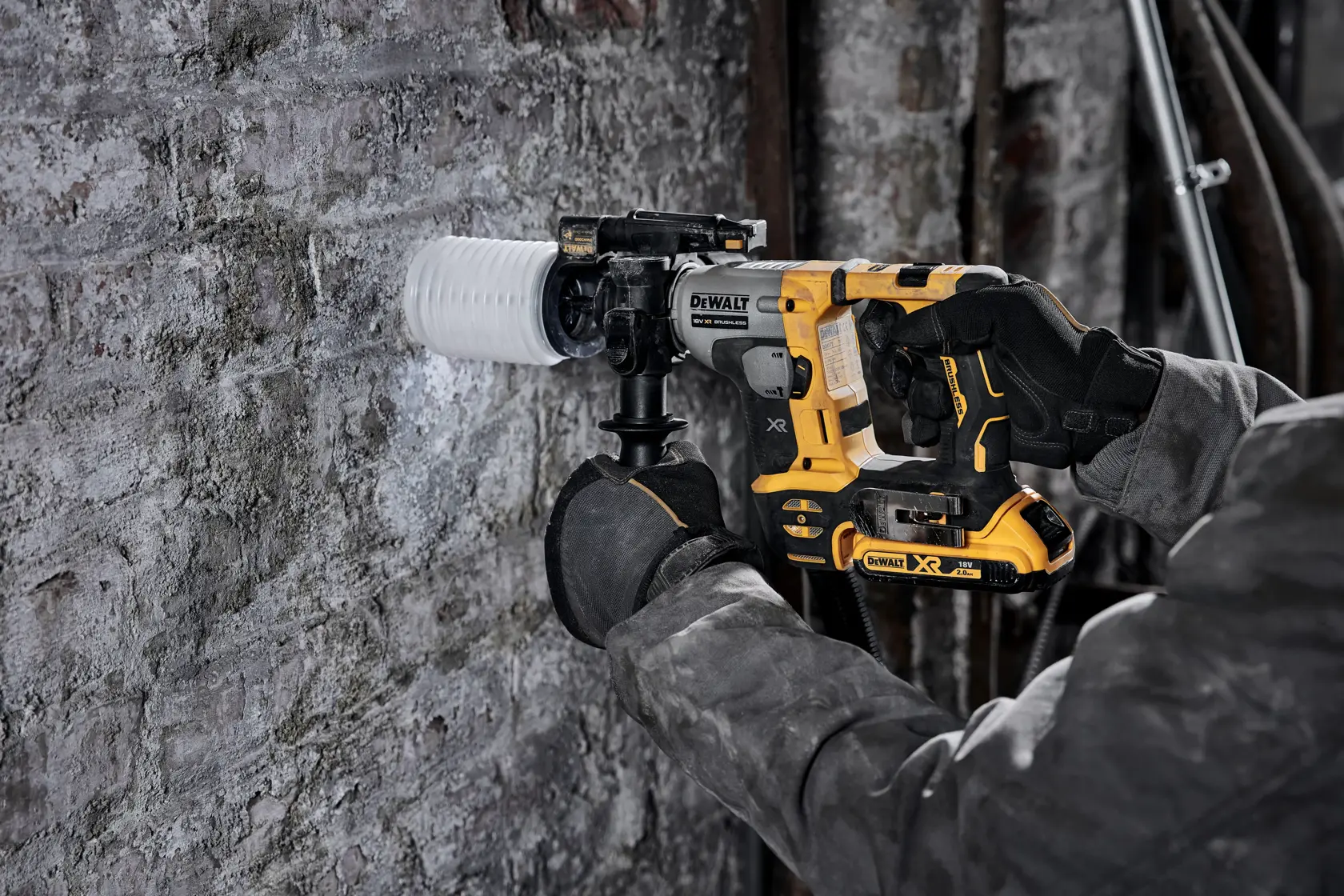 Person drills masonry wall with yellow DEWALT DCH172N rotary hammer and dust collection attachment.