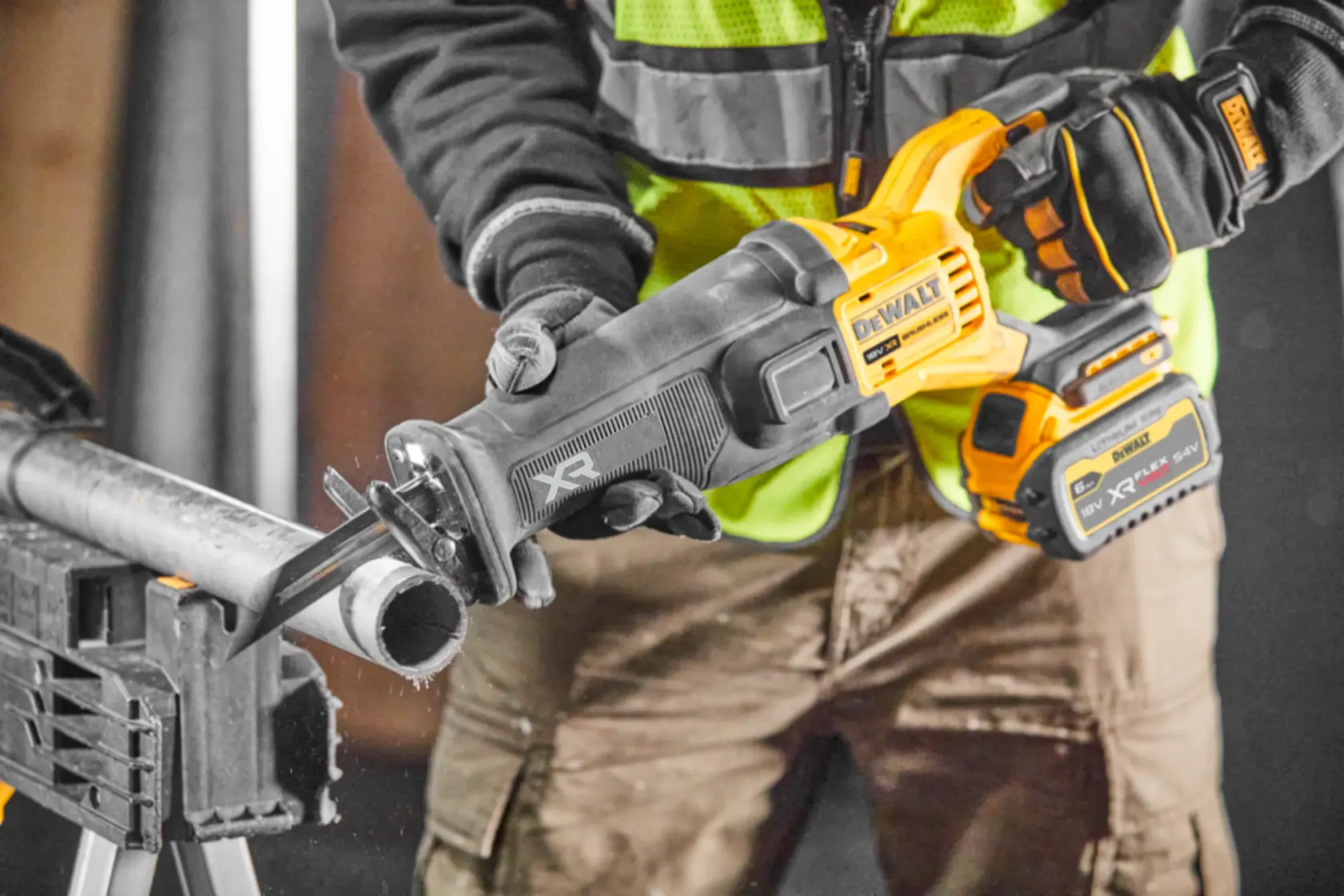 Sierra recíproca inalámbrica DEWALT corta tubo metálico, operada por trabajador con guantes y chaleco.