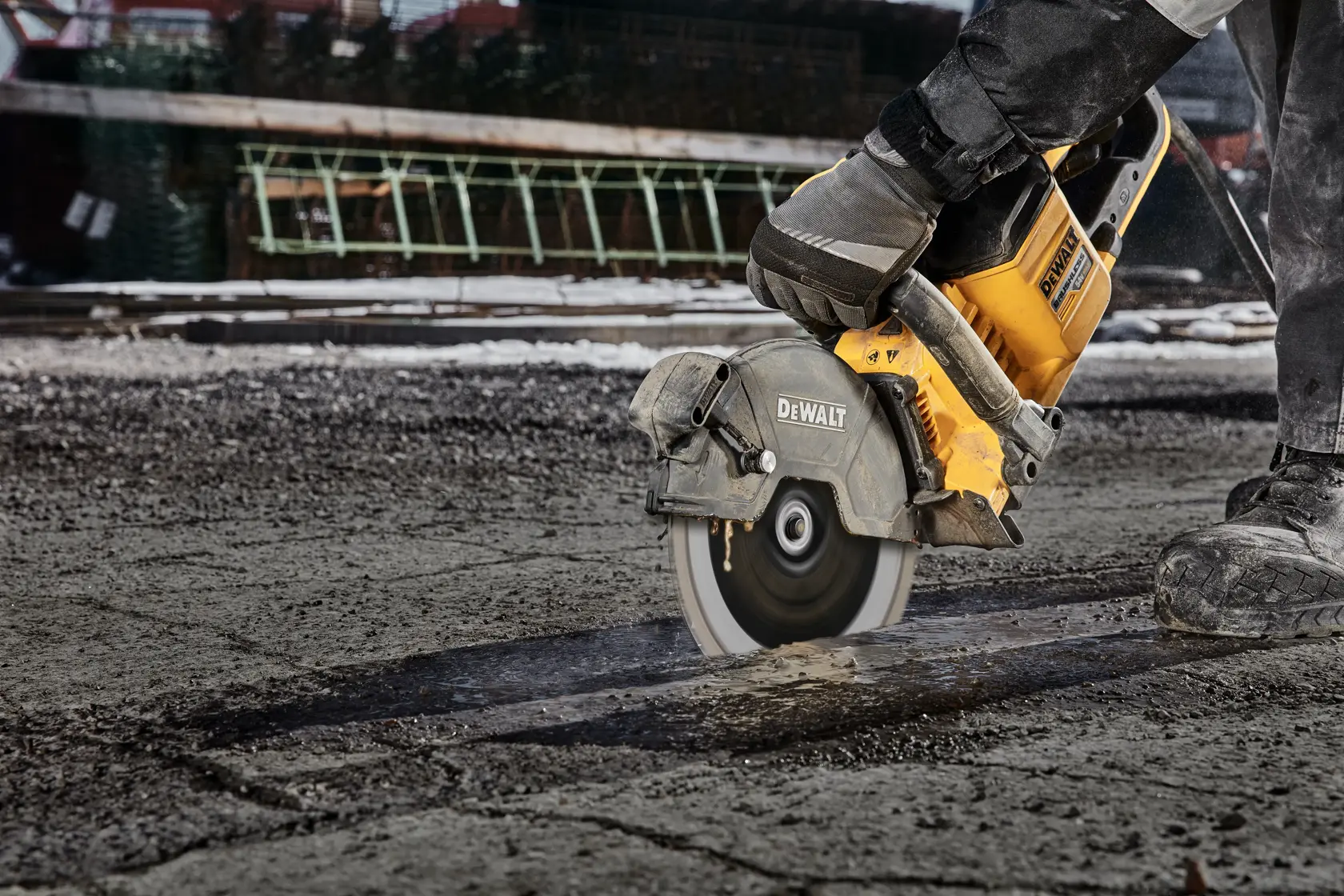 DEWALT power saw cutting through asphalt or concrete on an outdoor construction site.