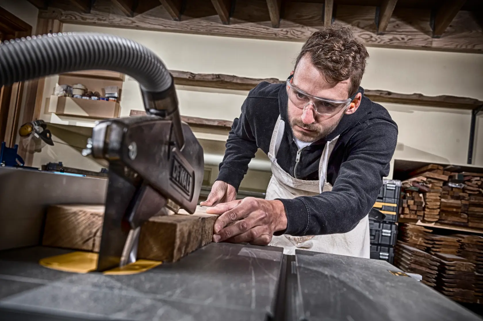 Person schneidet Holzplatten mit einer DEWALT Maschine in einer Werkstatt; Gesicht ist unscharf.