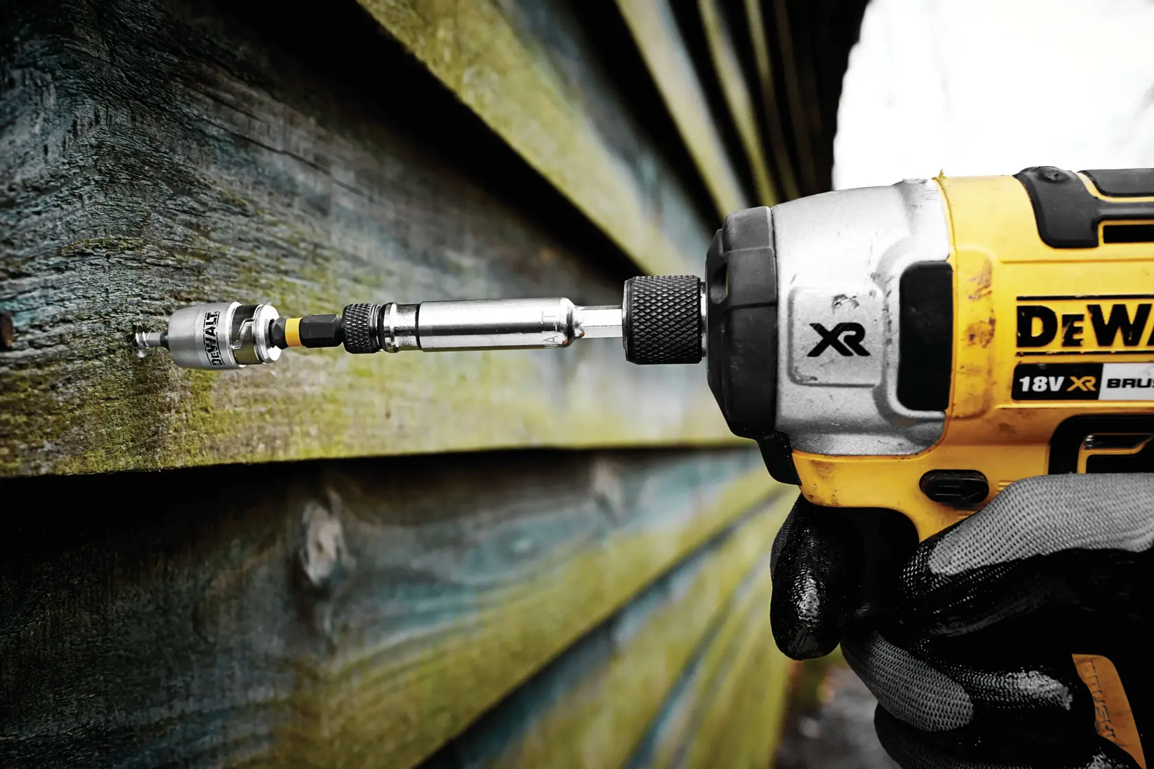Taladro DEWALT atornillando en revestimiento de madera, primer plano de la herramienta en uso.