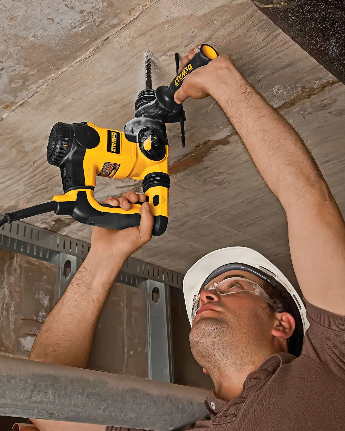 Person bohrt mit DEWALT Hammerbohrer in Betondecke. Gesicht aus Datenschutzgründen verschwommen.